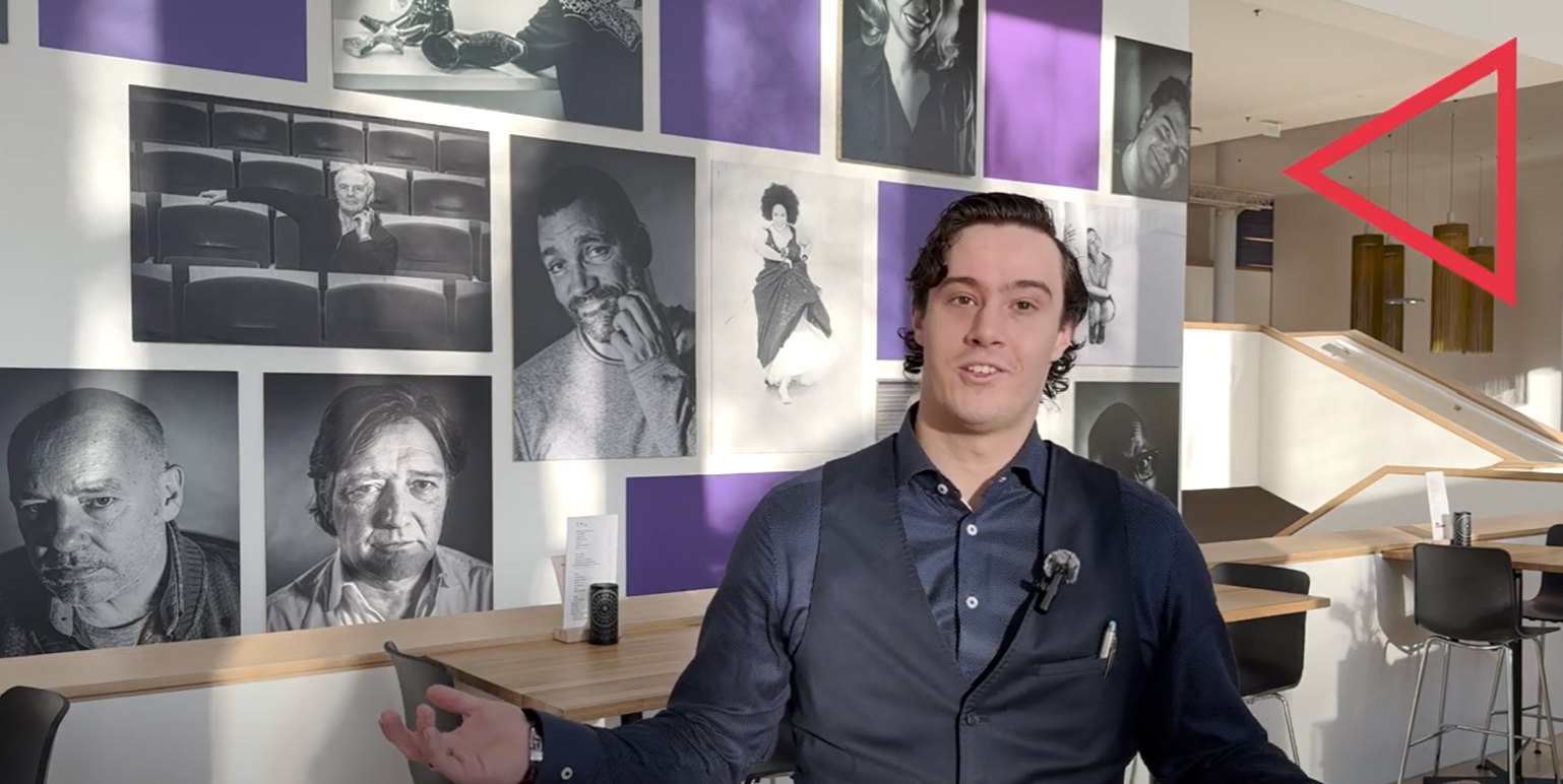 Student staat voor een muur met zwart-wit foto's