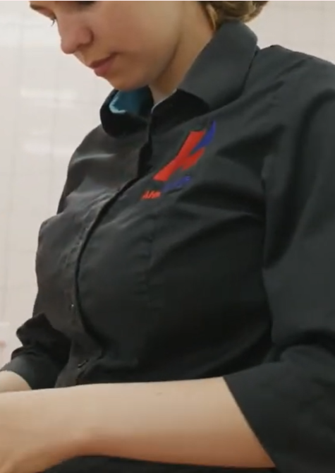 Student met zwart shirt en logo op de borst in een keuken.