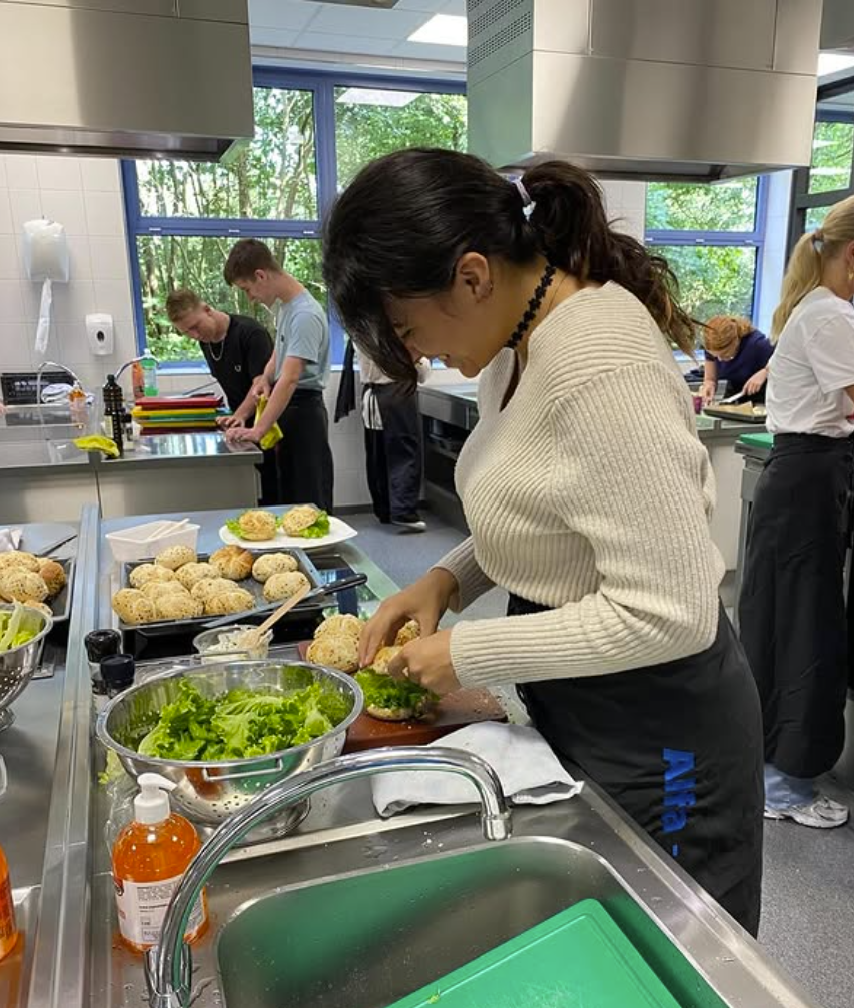 Studenten bereiden samen eten in een keuken tijdens een kookles.