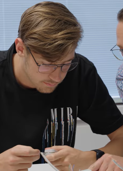 Twee studenten aan tafel bezig met de binnenkant van computers.