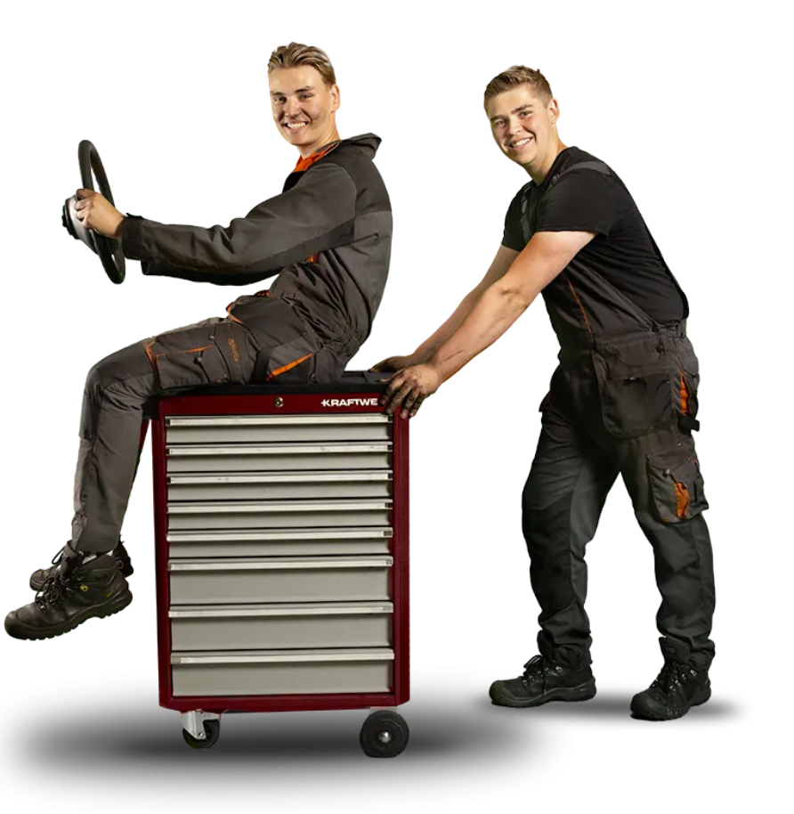 Twee studenten in overall doen alsof ze rijden met een rode gereedschapskist op wieltjes.