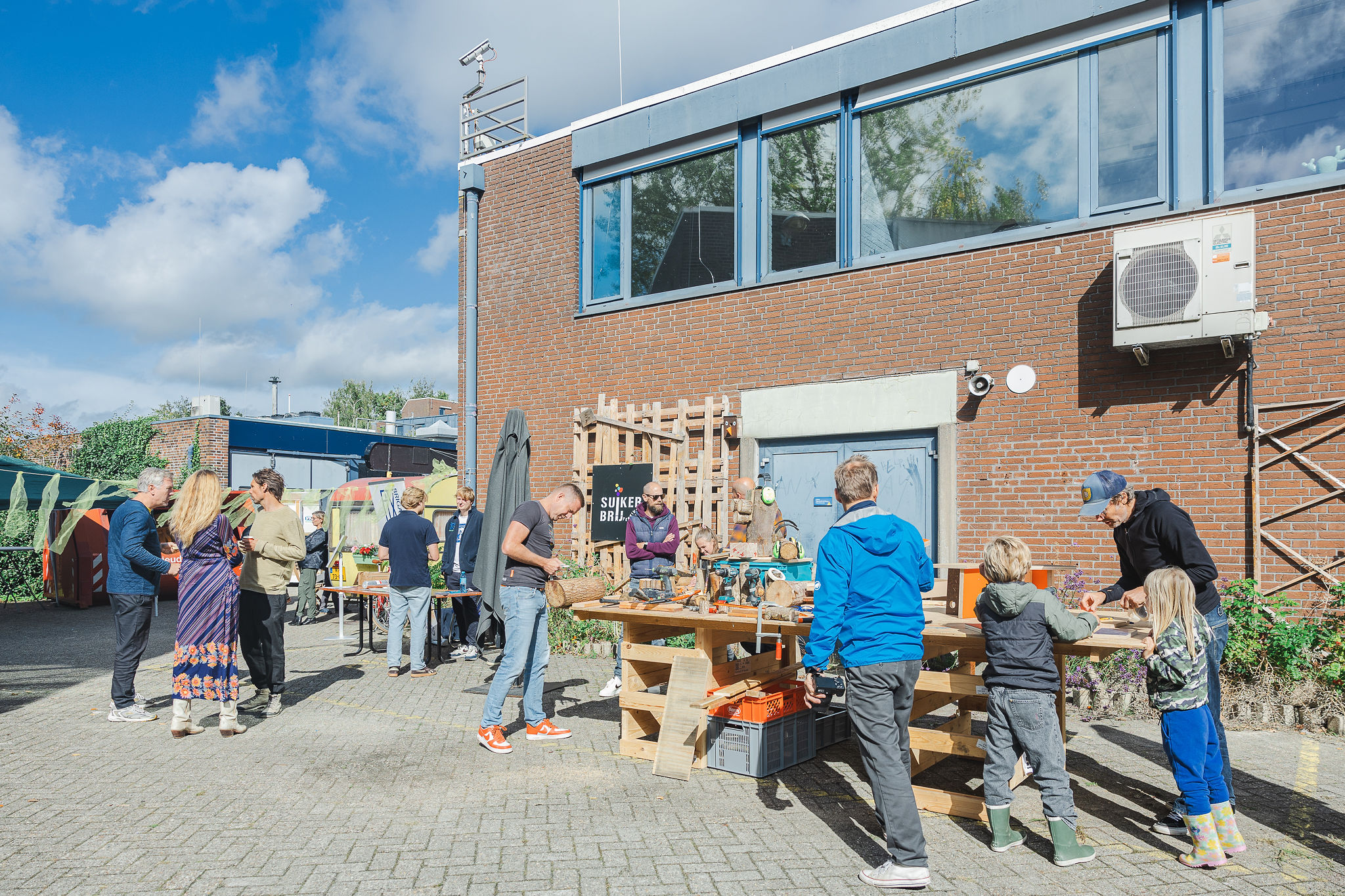 Mensen lopen op het terrein van de Bouwhub050 buiten rond op het Suikerbrij Festival
