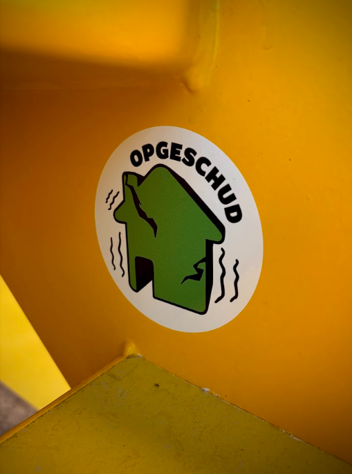 Sticker met het logo van Opgeschud, onderdeel van een door studenten Mediavormgeving ontworpen huisstijl. Het ontwerp ondersteunt een jongerenparticipatieproject waarbij jongeren uit het aardbevingsgebied meedenken over de toekomst van Groningen.